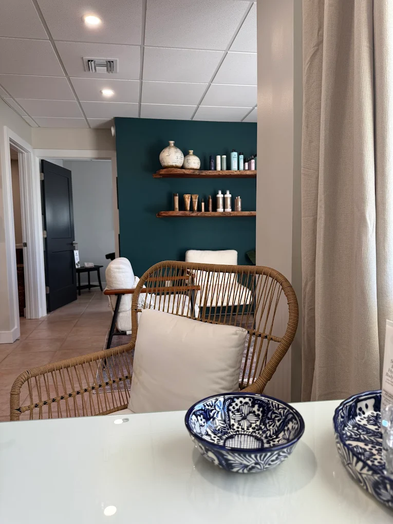 Vista Beauty Bar lounge with teal accent wall and rattan seating